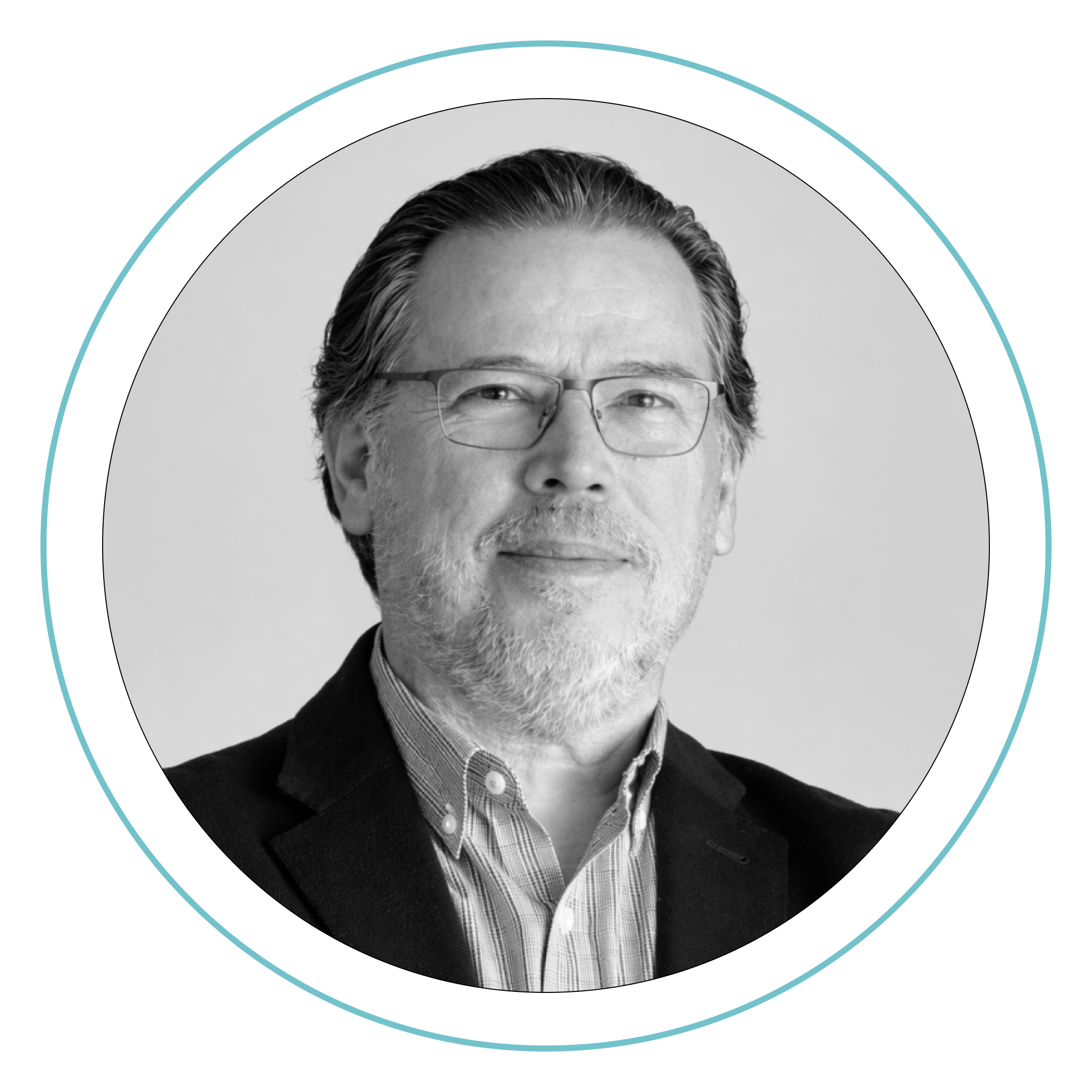 Un hombre de mediana edad con gafas, pelo corto canoso y barba sonríe ligeramente. Lleva camisa de cuello y americana oscura. La foto es en blanco y negro, dentro de un marco circular con un fino contorno azul.